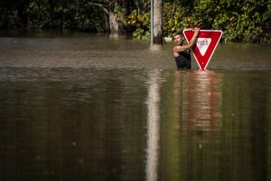 A man holds onto a yield sign after trying to swim out to help a stranded truck driver at NC 301 Highway and Tom Starling Road in Hope Mills on Sunday, Oct. 9, 2016. Both people were rescued.